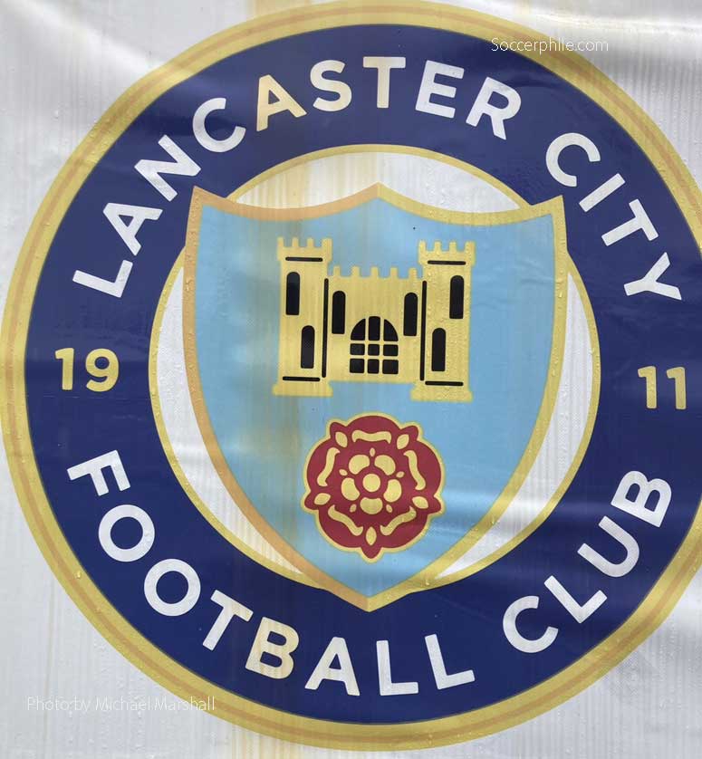 The team crest features Lancaster Castle and the Red Rose of Lancashire.