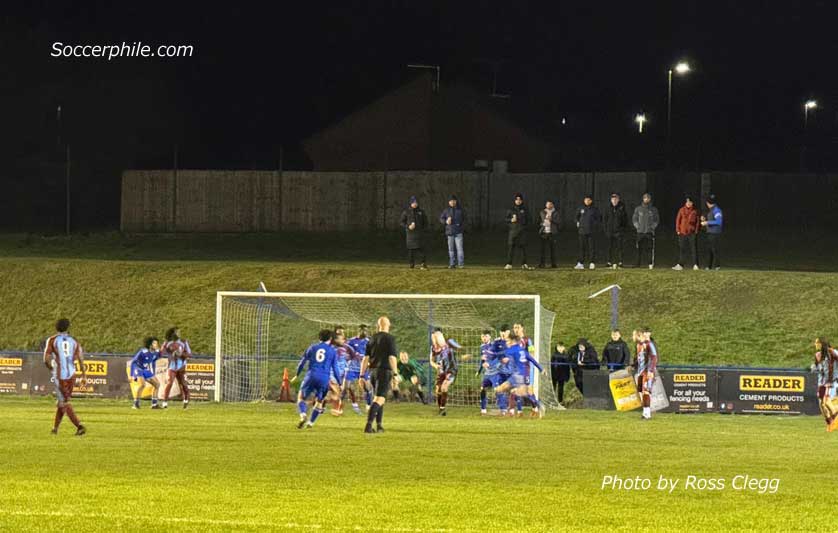 Standing on a grass bank behind one goal.